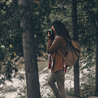 Capturing the view. Full Length of young modern woman with backpack photographing nature while hiking in the woods